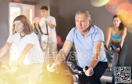 Elderly man working out on stationary bicycle in gym
