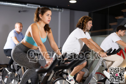 Young girl doing cardio workout on exercise bike in gym