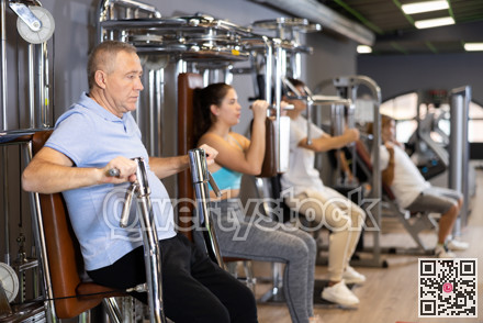 Pensioner is engaged in simulator - develops biceps and triceps