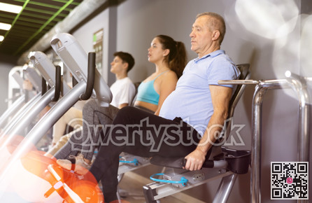 Elderly man working out on stationary bicycle in gym