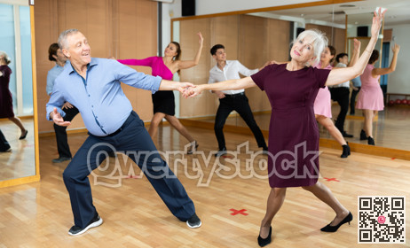 Elderly pair practicing ballroom dance in dance studio