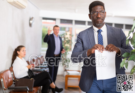 Upset adult man with documents standing in reception