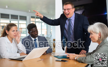 Angry middle-aged man shouting at his business partners sitting around table