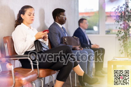 Young woman sitting in line at reception with phone