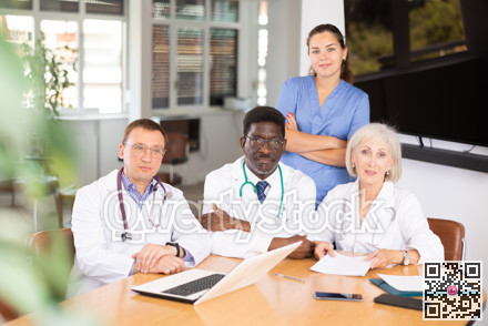 Group of different medical people posing at table in office