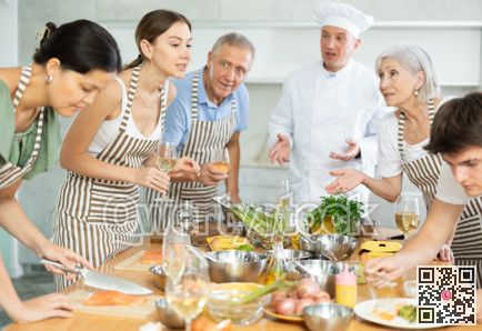 Cheerful woman drinking wine and talking during group culinary masterclass