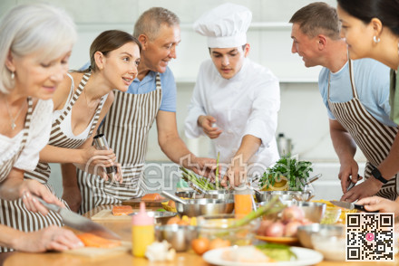 Young guy cook teaches to cook group of people