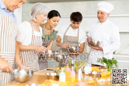 Adult male cook teaches cooking to group of people
