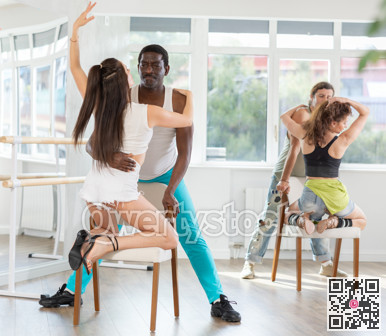 Woman in heels dances with man kneeling on chair