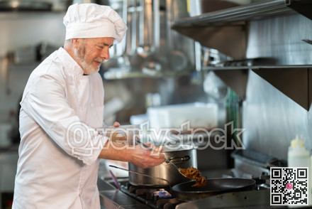 Senior male cook preparing dish in restaurant kitchen