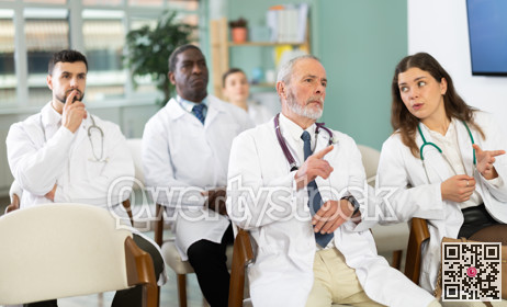 Male doctor listens to lecture with colleagues in auditorium