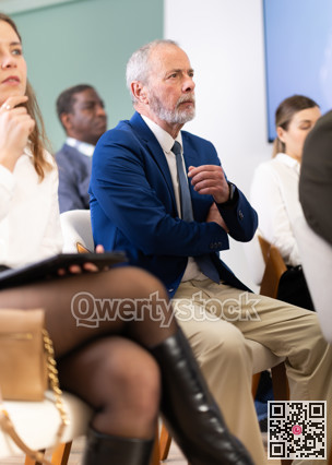 Eldery man listens to presentation in conference room