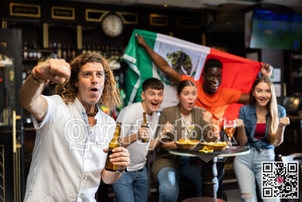 Happy international footbal supporters holding up the flag of Mexico and drinking beer in the pub