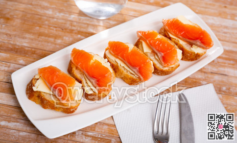 Delicious sandwiches with salmon and butter on white plate
