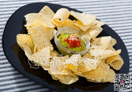Nachos chips with sauces on black plate