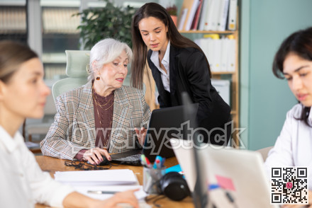 Young woman helping elderly woman with laptop