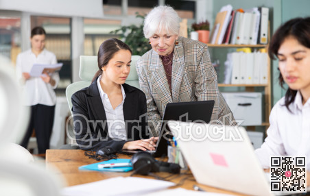 Elderly woman helping young woman with laptop