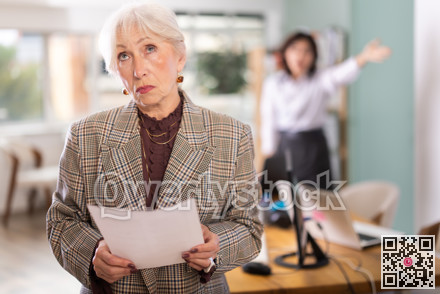 Upset mature woman being scolded by young manager in background