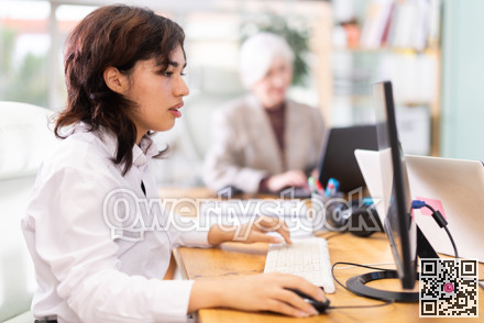 Young woman works on laptop with female colleagues