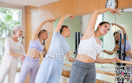 Female ballet instructor adjusting students form in dancing school