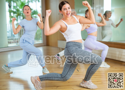 Active young woman practicing aerobic dance in training hall