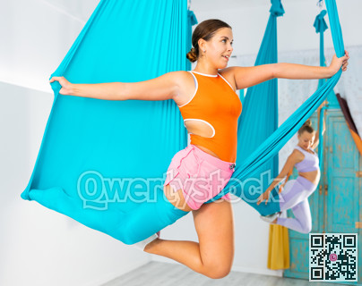 Girl doing unicorn pose in suspended hammock at aerial yoga training