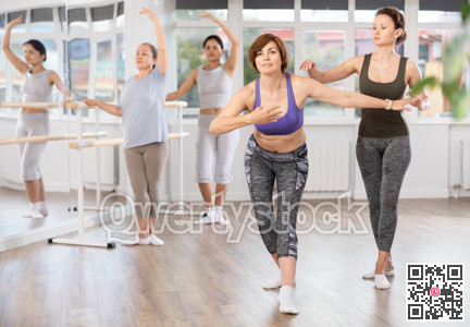 Adult woman teacher correcting beginning dancers