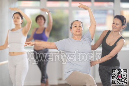 Adult woman teacher correcting beginning dancers
