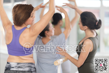 Rear view of woman practicing ballet postures at amateur group rehearsal