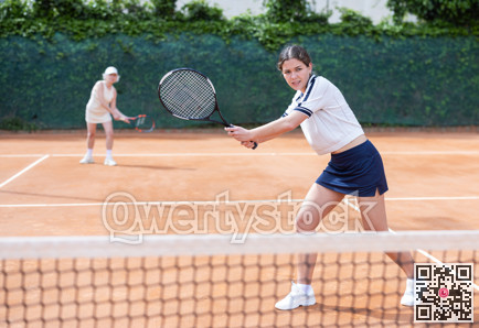 Young woman playing doubles tennis on court