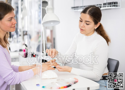 Manicurist files the nails of a young female client