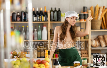 Seductive girl saleswoman dancing topless behind grocery store counter
