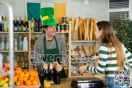 Friendly seller in Irish outfit serving beer to woman for St. Patrick day