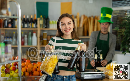 Cheerful woman shopping for beer and snacks in St. Patrick Day-themed store