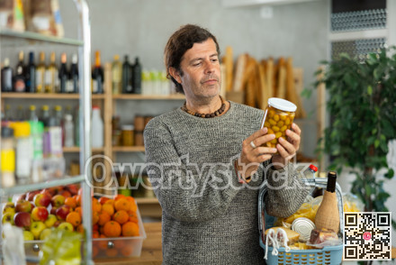 Thoughtful man choosing marinated olives in grocery store