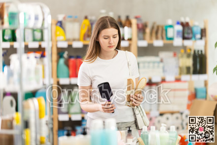 Female shopper in spring clothes chooses best comb in supermarket