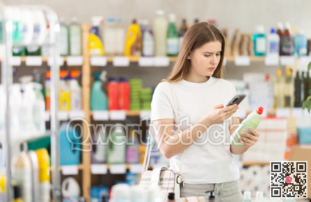 Young fmale shopper scans QR code on label of dishwashing for windows using smartphone