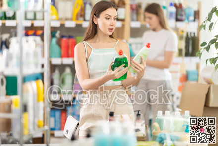 Young woman chooses dishwashing detergent in store