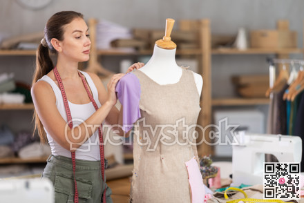 Girl designer works with mannequin and dress billet