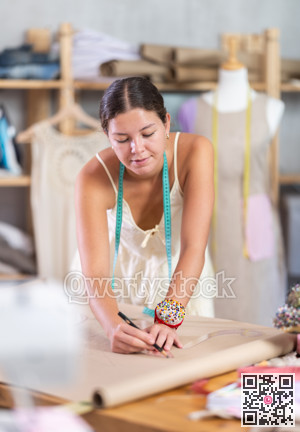 Using curve ruler, woman tailor draws dress diagram scheme on paper