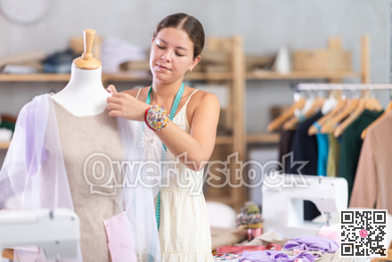 Girl designer works with mannequin and dress billet