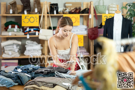 Female shopper scanning trousers tag in clothing store