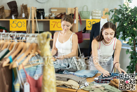 Young women customer making choice and elect trousers or shorts in store