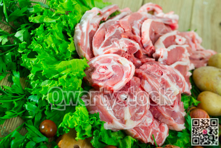 Pieces of fresh lamb meat on a wooden desk with vegetables