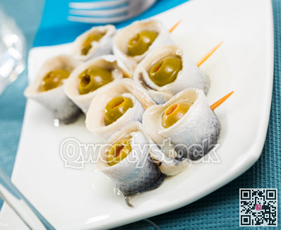 Appetizing herring rolls with olives on skewers