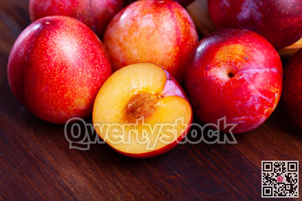 Close-up of fresh juicy red plums on wooden surface