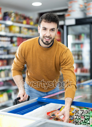 Man choosing frozen food in supermarket. Man purchasing goods in store