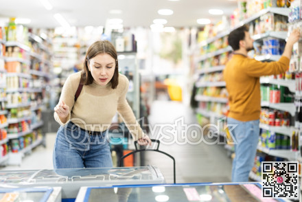 Young woman choosing frozen food in grocery store