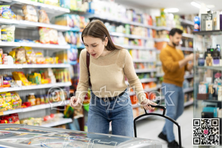 Young woman choosing frozen food in grocery store