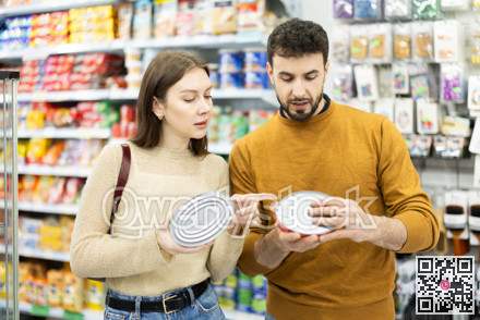 Couple of shoppers are choosing canned fish in food store